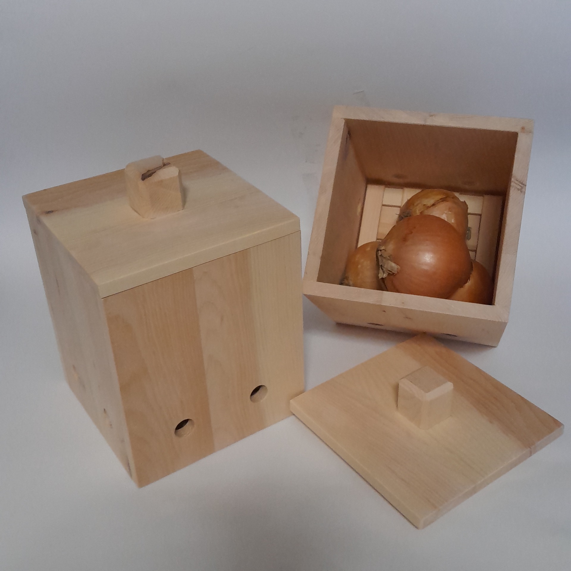 Handgefertigter Zwiebeltopf und Zwiebelbox aus Zirbenholz mit herausnehmbarem Belüftungsgitter am Boden und Knoblauch.